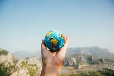 Hand mit Globus vor Bergpanorama